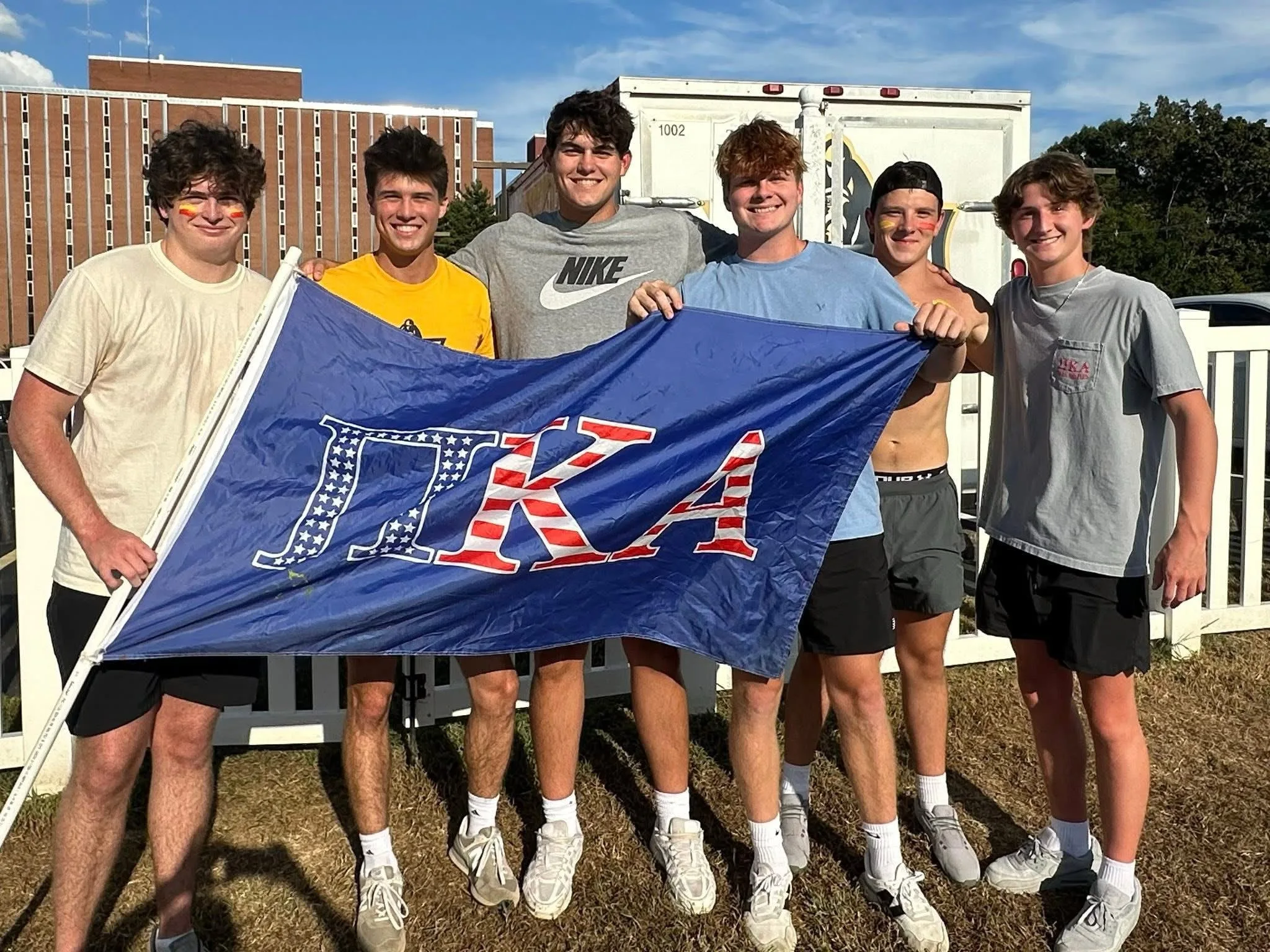 Pi Kappa Alpha members with chapter flag on sunny day